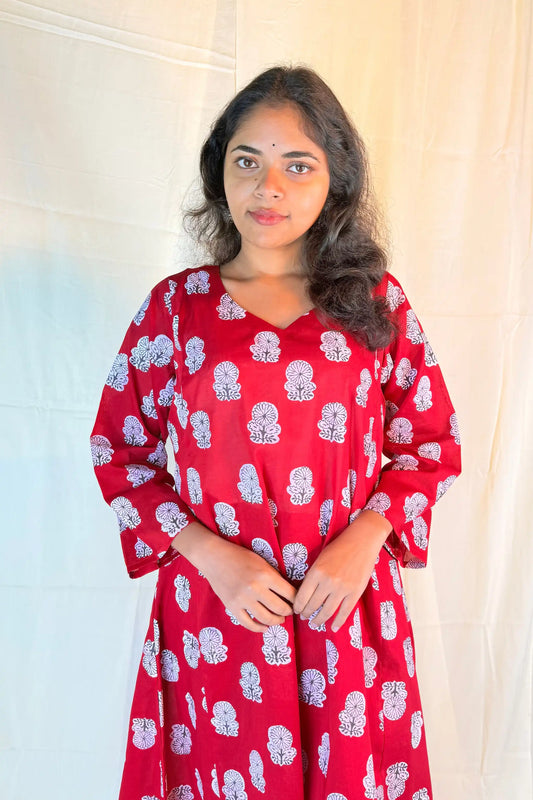 Woman wearing a red dress with white floral patterns against a neutral background