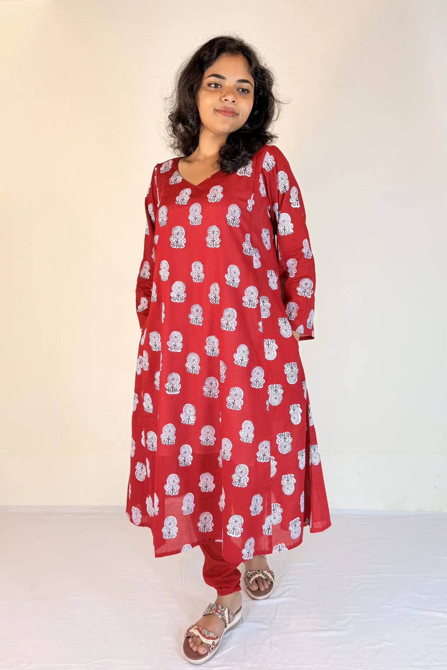 Woman wearing a red dress with white patterns on a white background