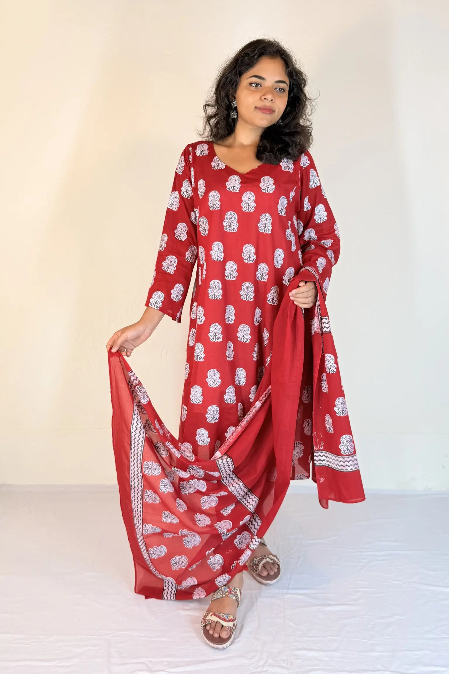 Woman wearing a red and white patterned outfit with a scarf against a white background