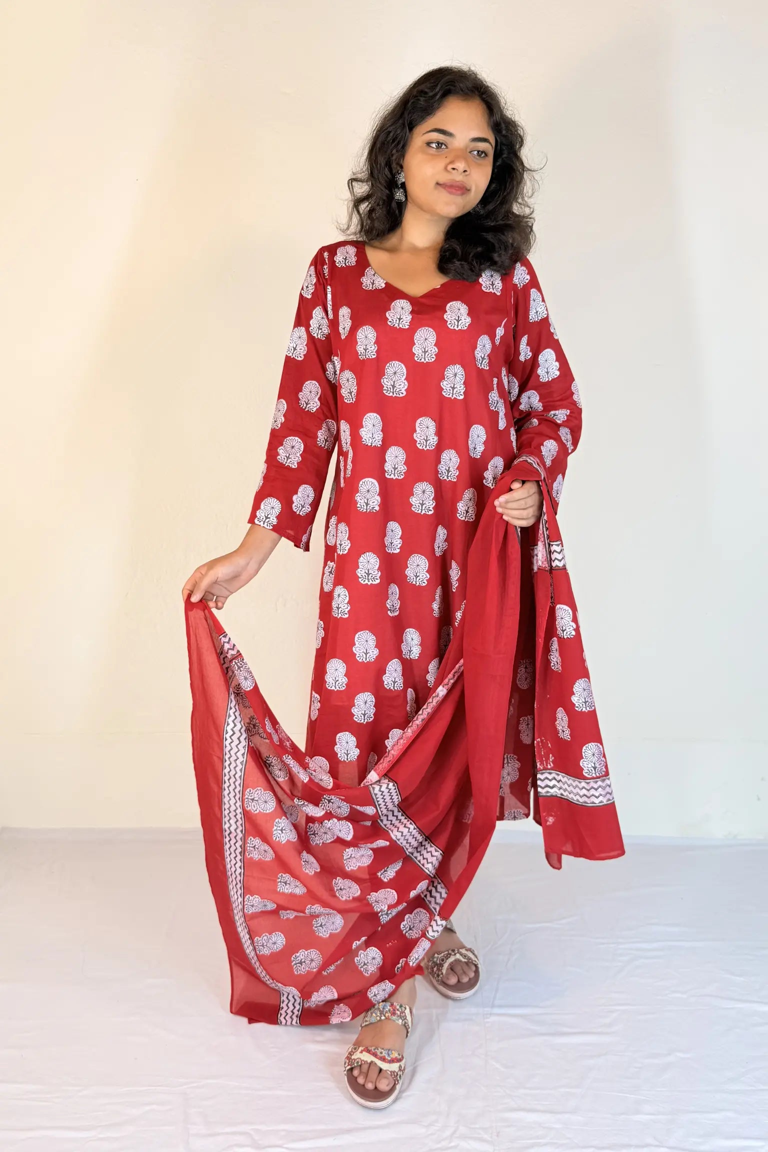 Woman wearing a red and white patterned outfit with a scarf against a white background