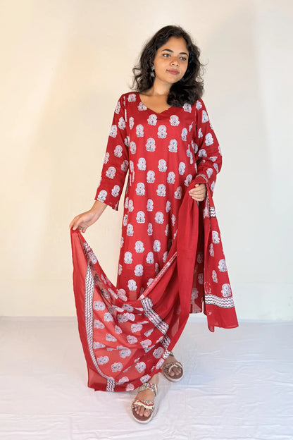 Woman wearing a red and white patterned outfit with a scarf against a white background