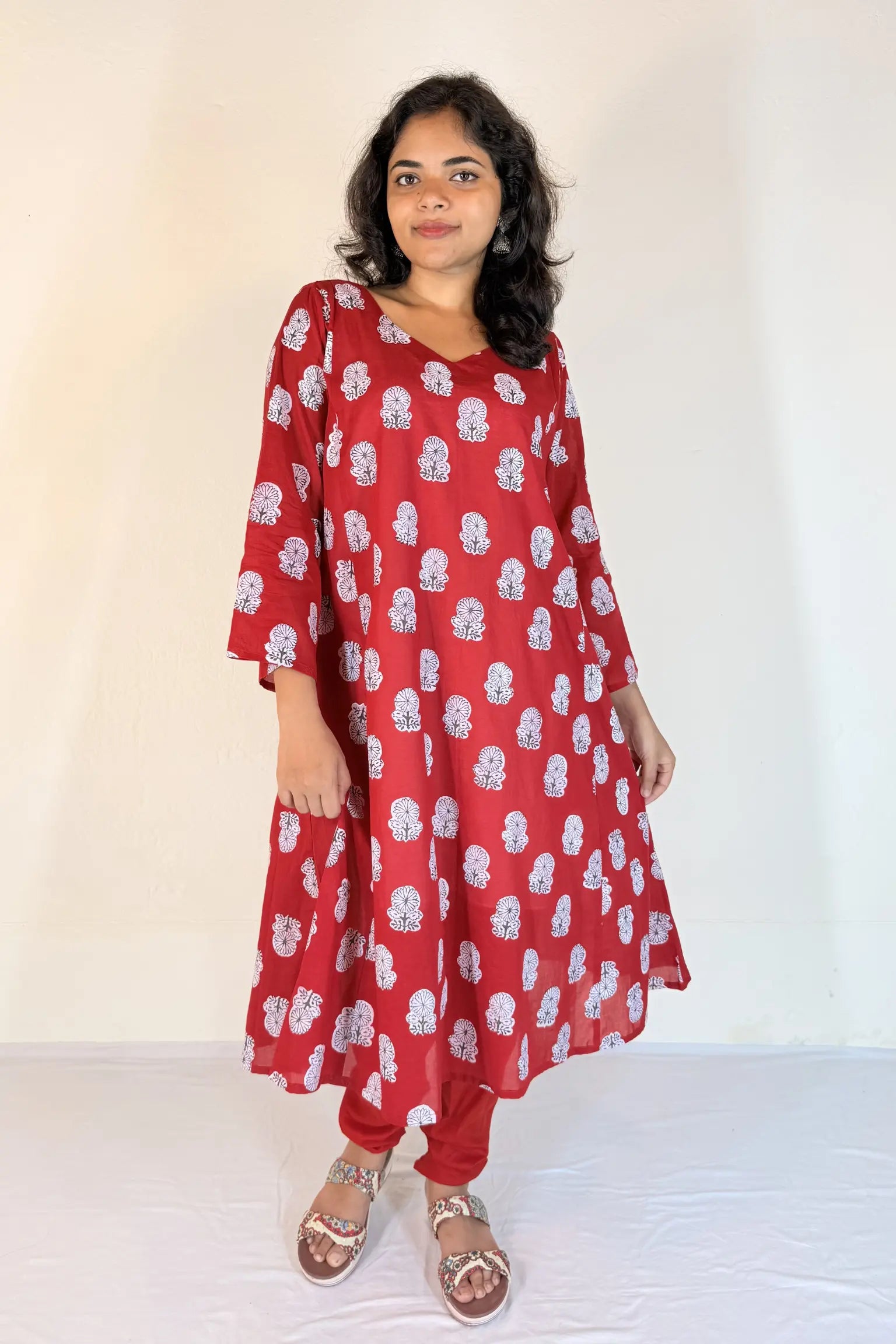 Woman wearing a red floral dress against a white background