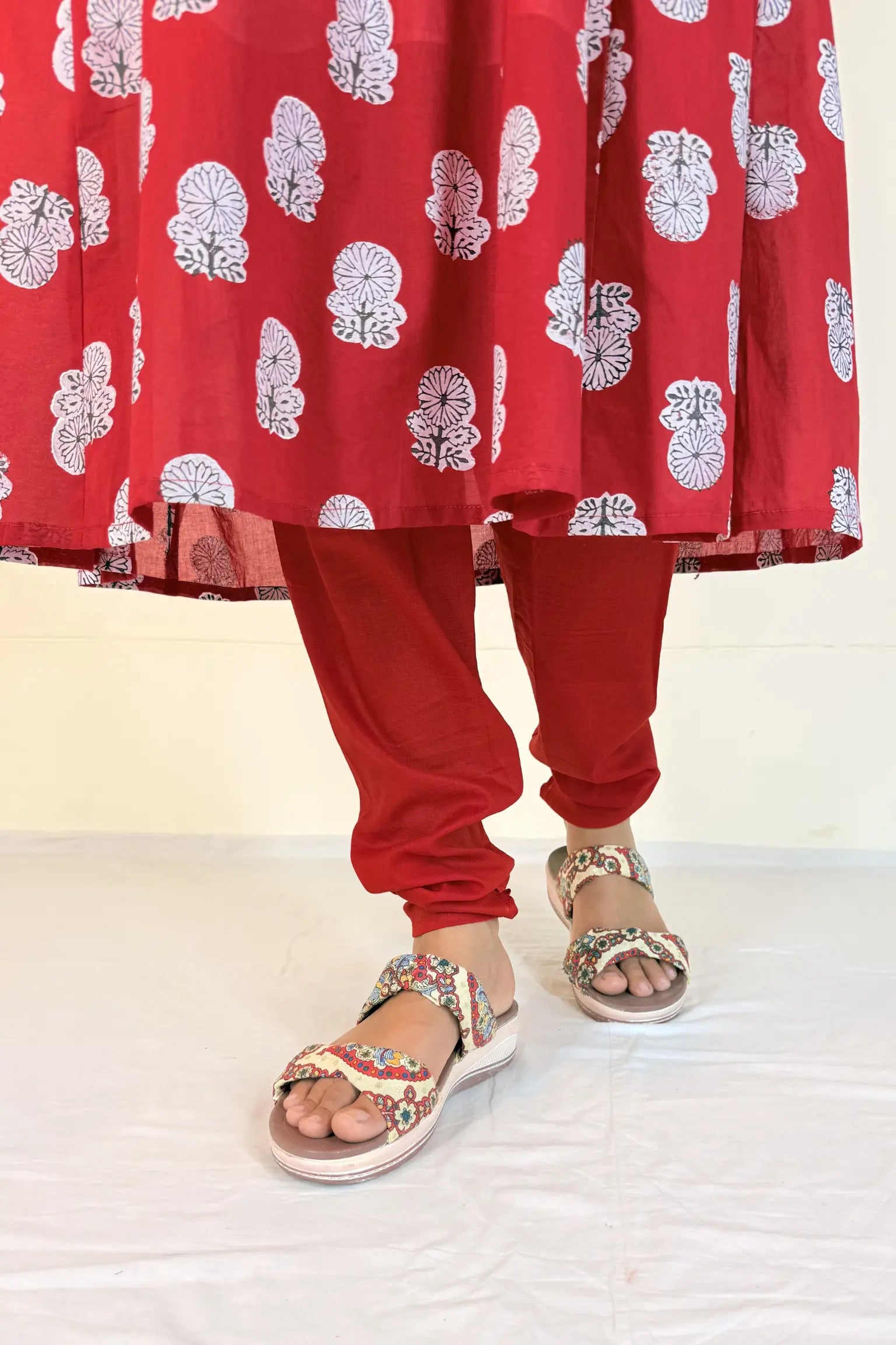 Red traditional outfit with white floral patterns on a plain background
