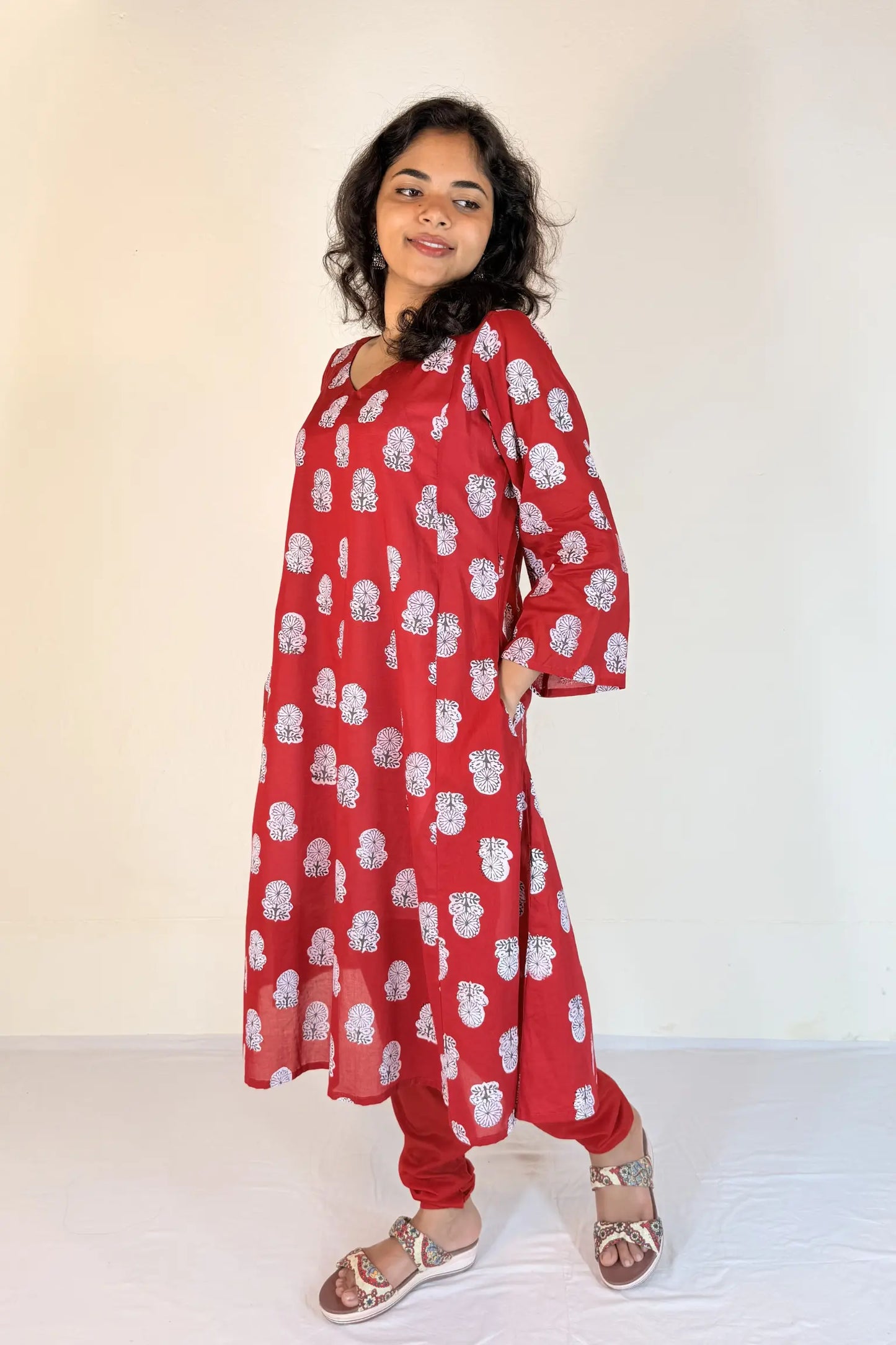 Woman wearing a red floral dress against a white background