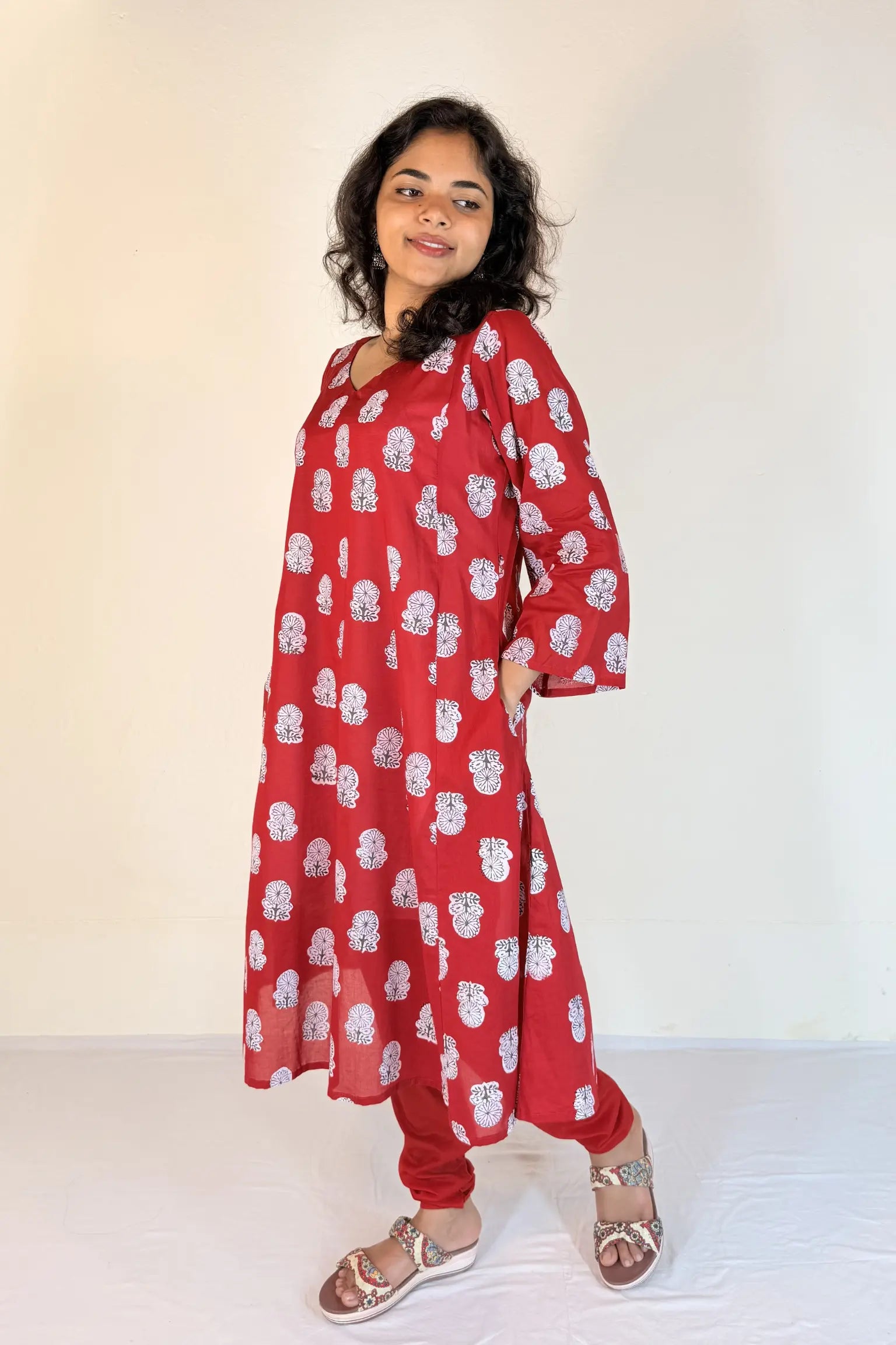 Woman wearing a red floral dress against a white background