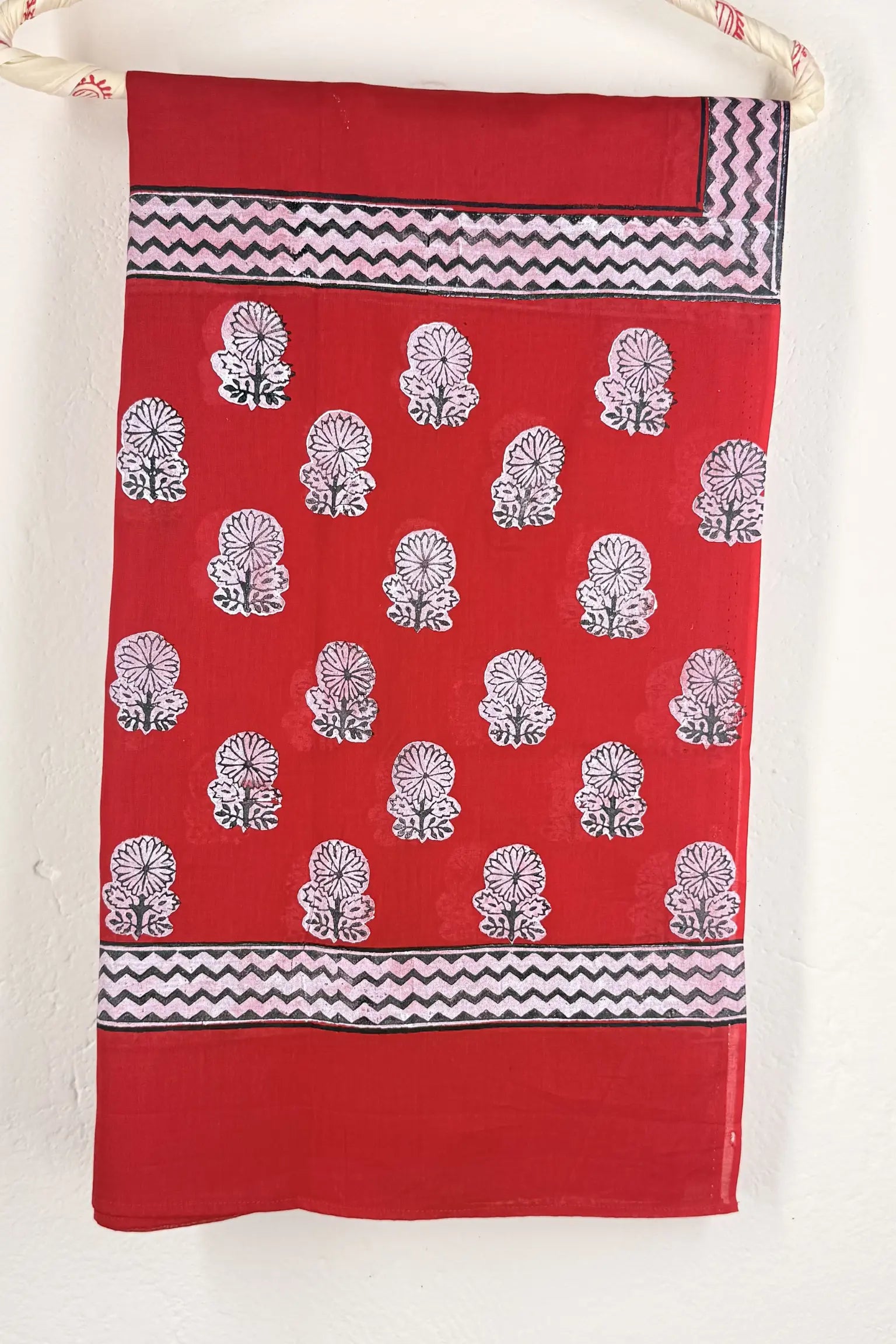 Red towel with black and white patterns hanging on a rack