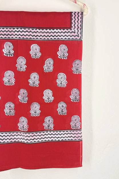 Red fabric with white floral patterns and black zigzag borders on a white background