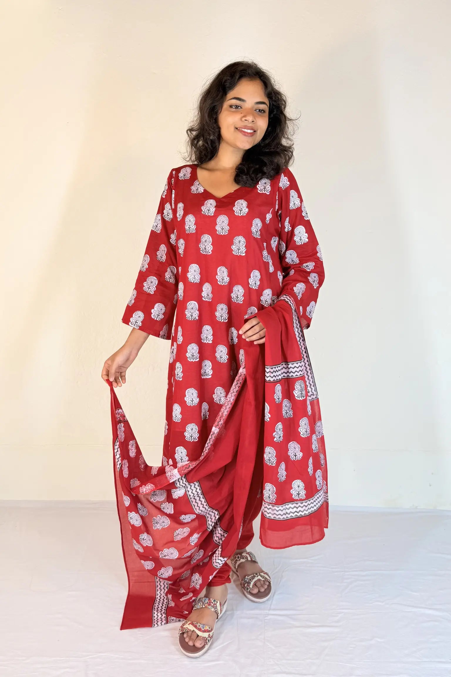 Woman wearing a yellow traditional outfit with white patterns on a plain background