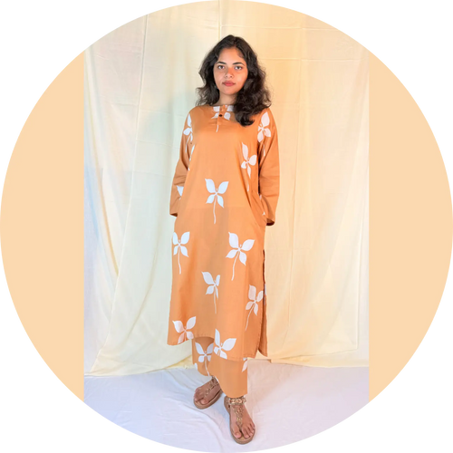 Woman wearing an orange dress with white floral patterns against a plain background