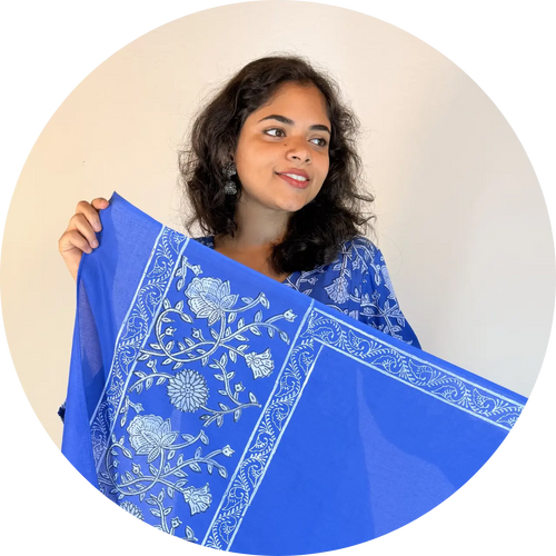 Woman holding a blue scarf with white floral patterns against a beige background