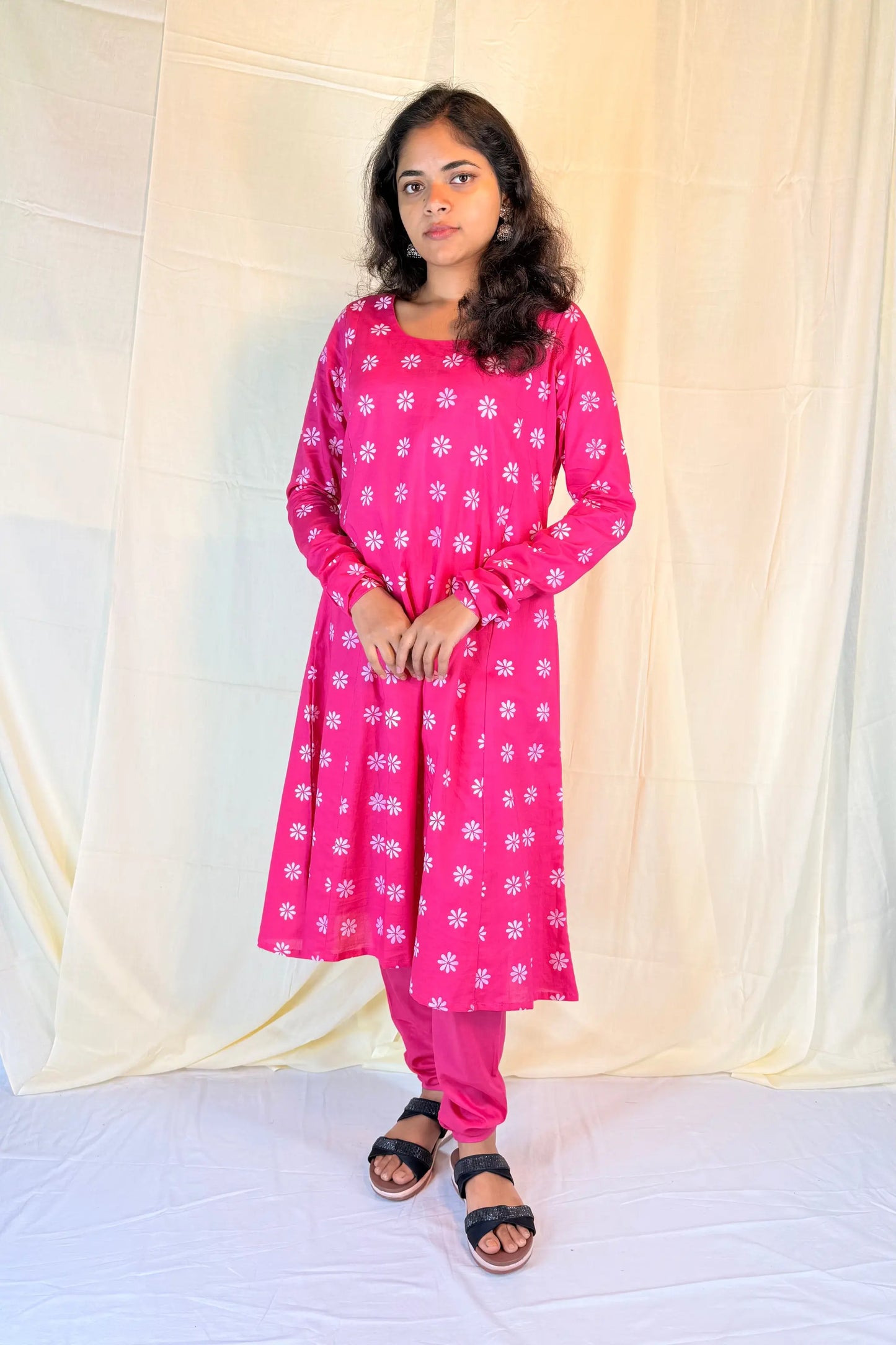 Woman wearing a pink floral kurta with pink pants against a white background
