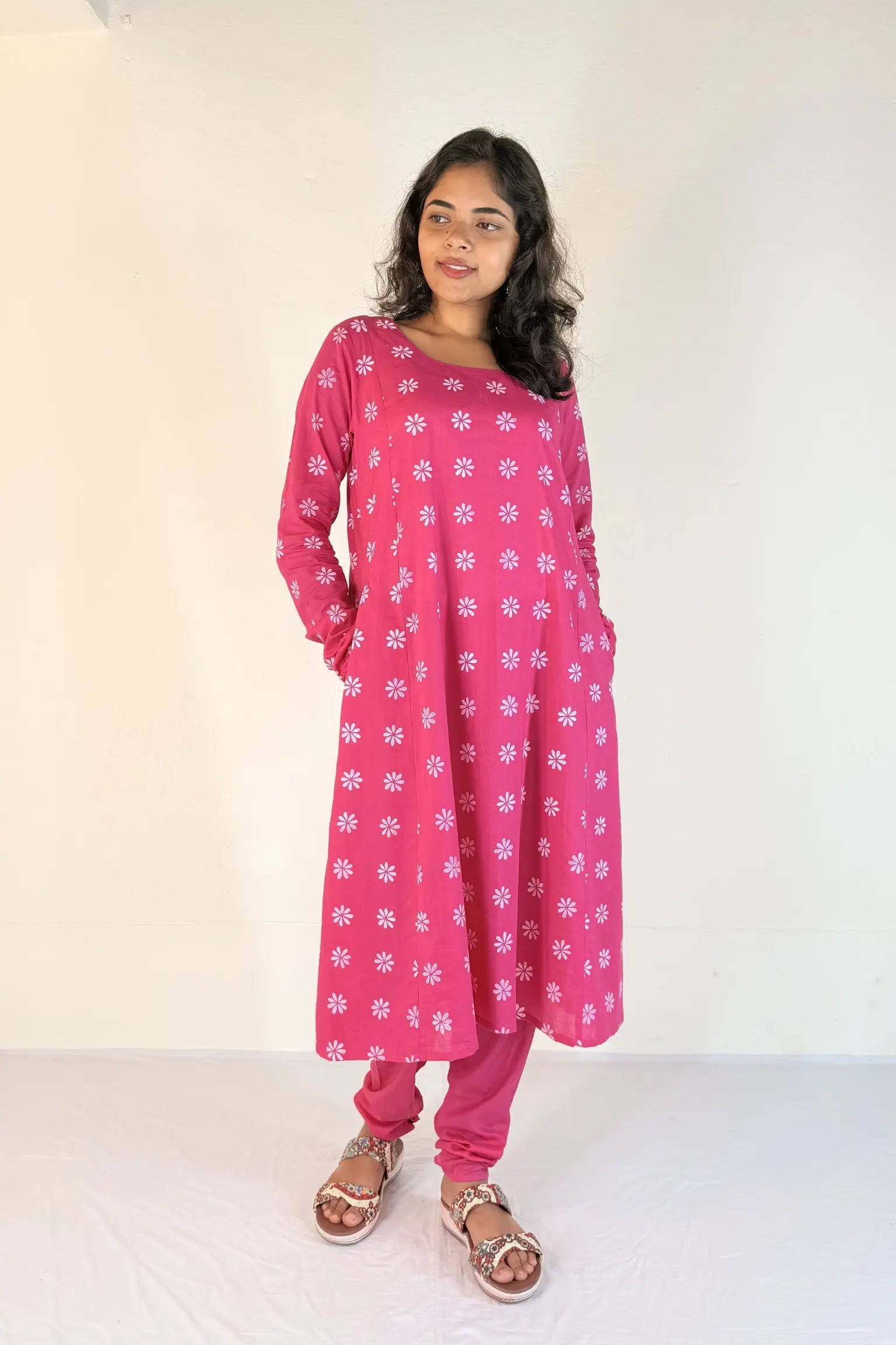 Woman wearing a pink floral dress and pants against a white background