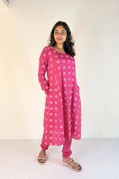 Woman wearing a pink dress with white patterns on a white background