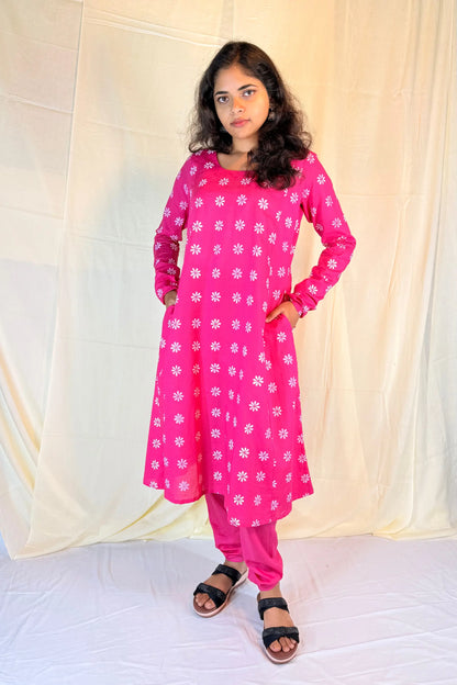 Person wearing a bright pink outfit with white floral patterns against a plain background