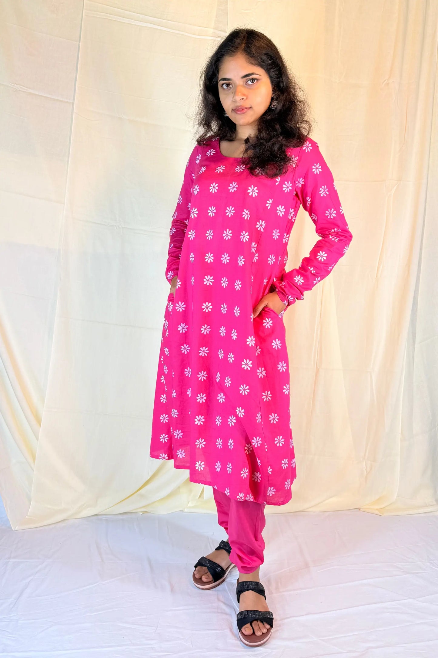 Person wearing a pink floral outfit against a beige background