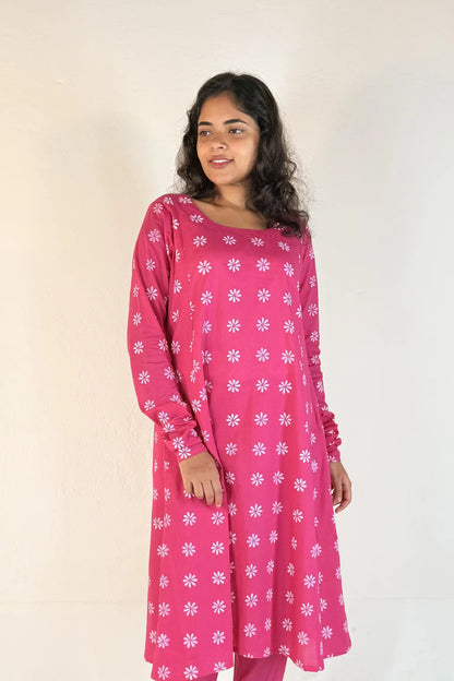 Woman wearing a pink kurta with white floral patterns on a plain background