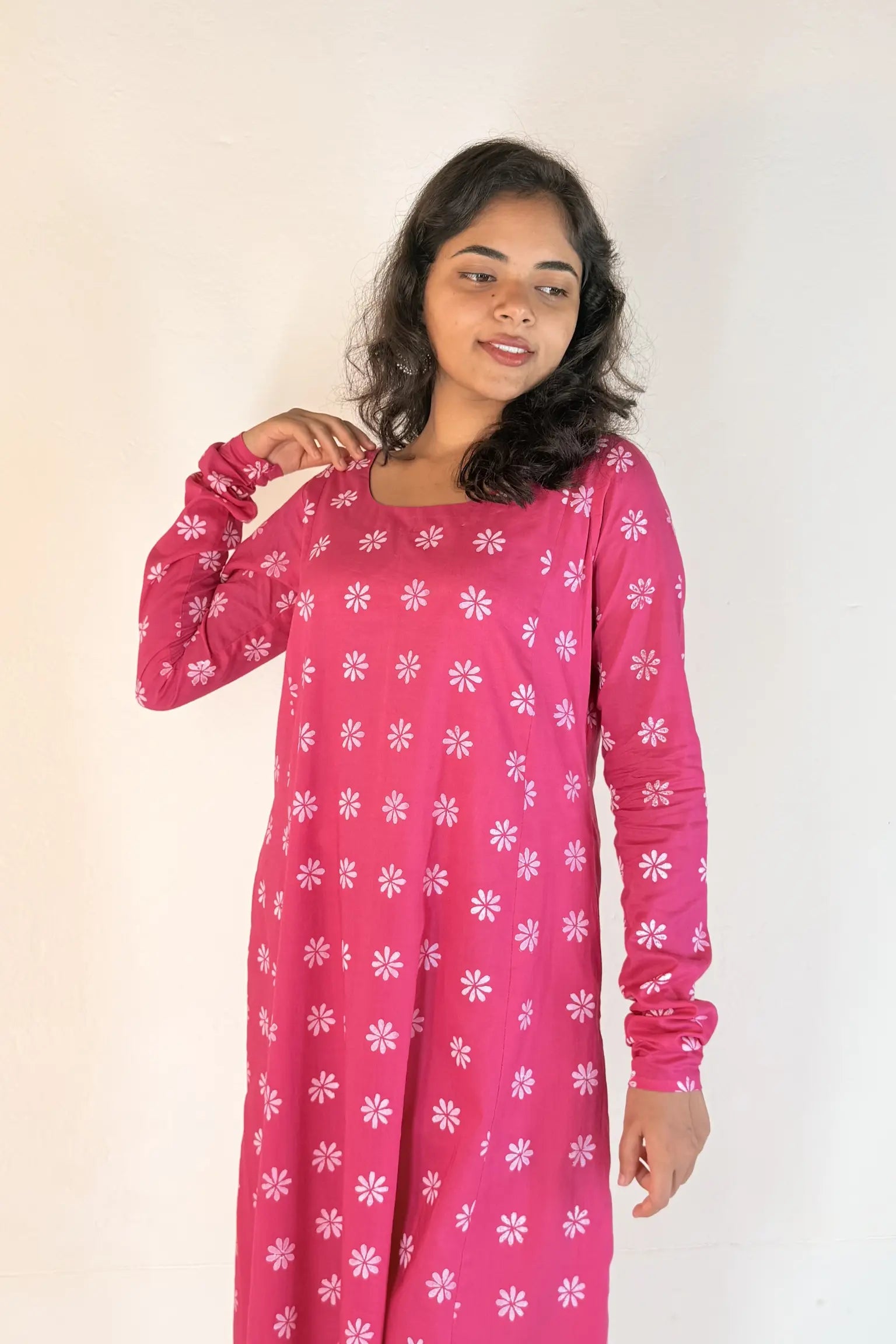Woman wearing a pink outfit with white floral patterns on a plain background