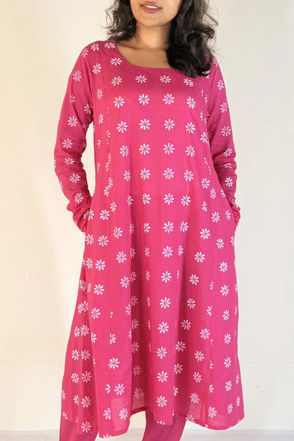 Woman wearing a pink dress with white floral pattern on a plain background