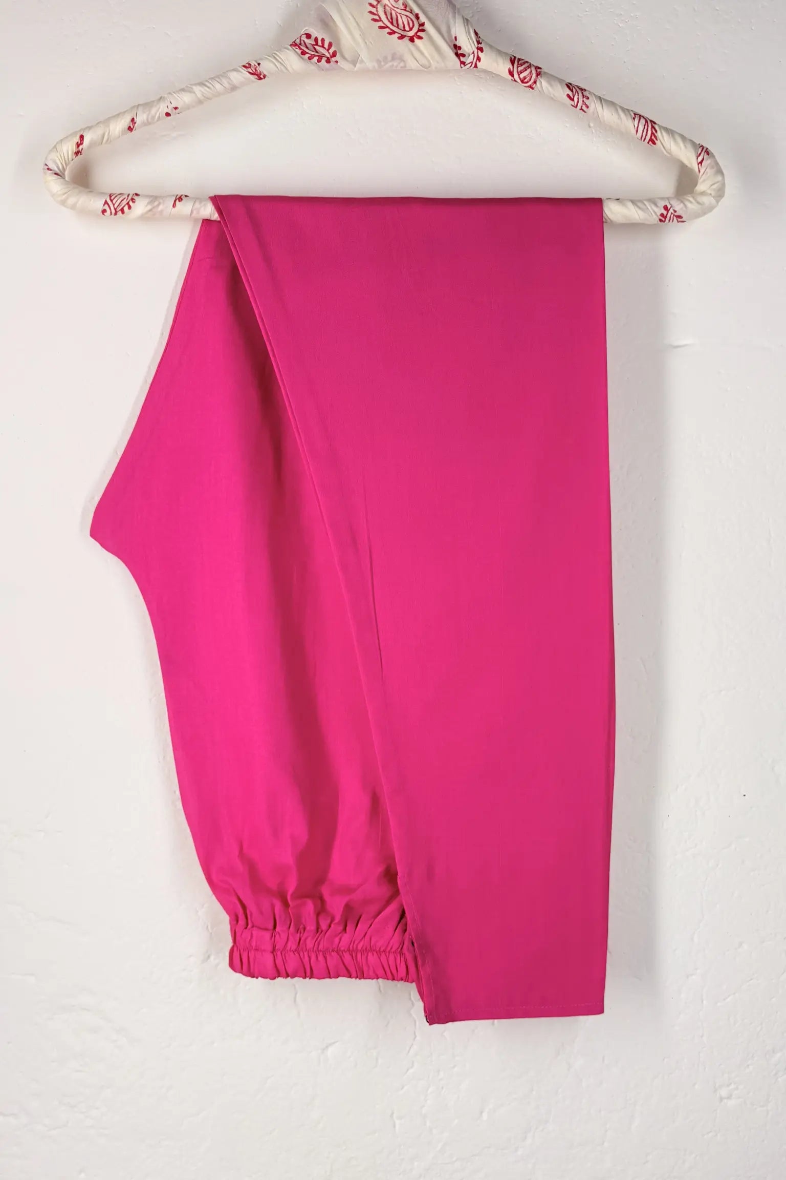 Pink cotton churidar on a hanger with floral pattern against a white background