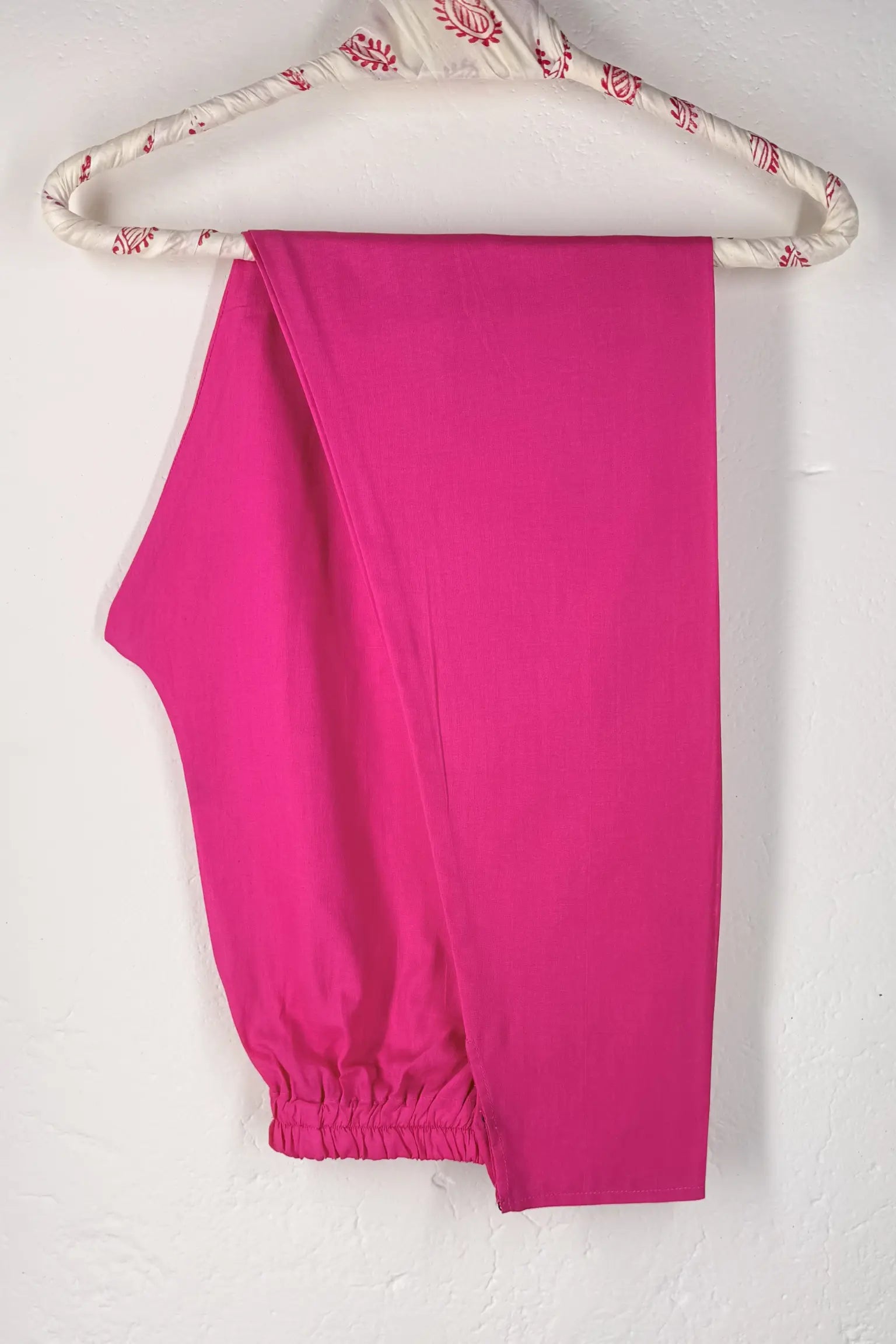 Pink cotton churidar on a hanger with floral pattern against a white background