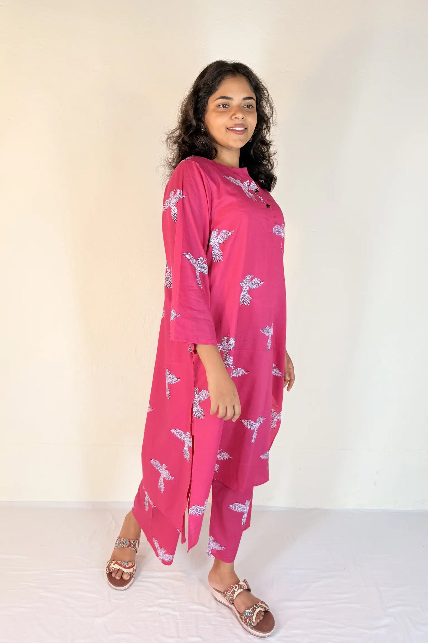 Woman wearing a pink dress with white patterns on a white background