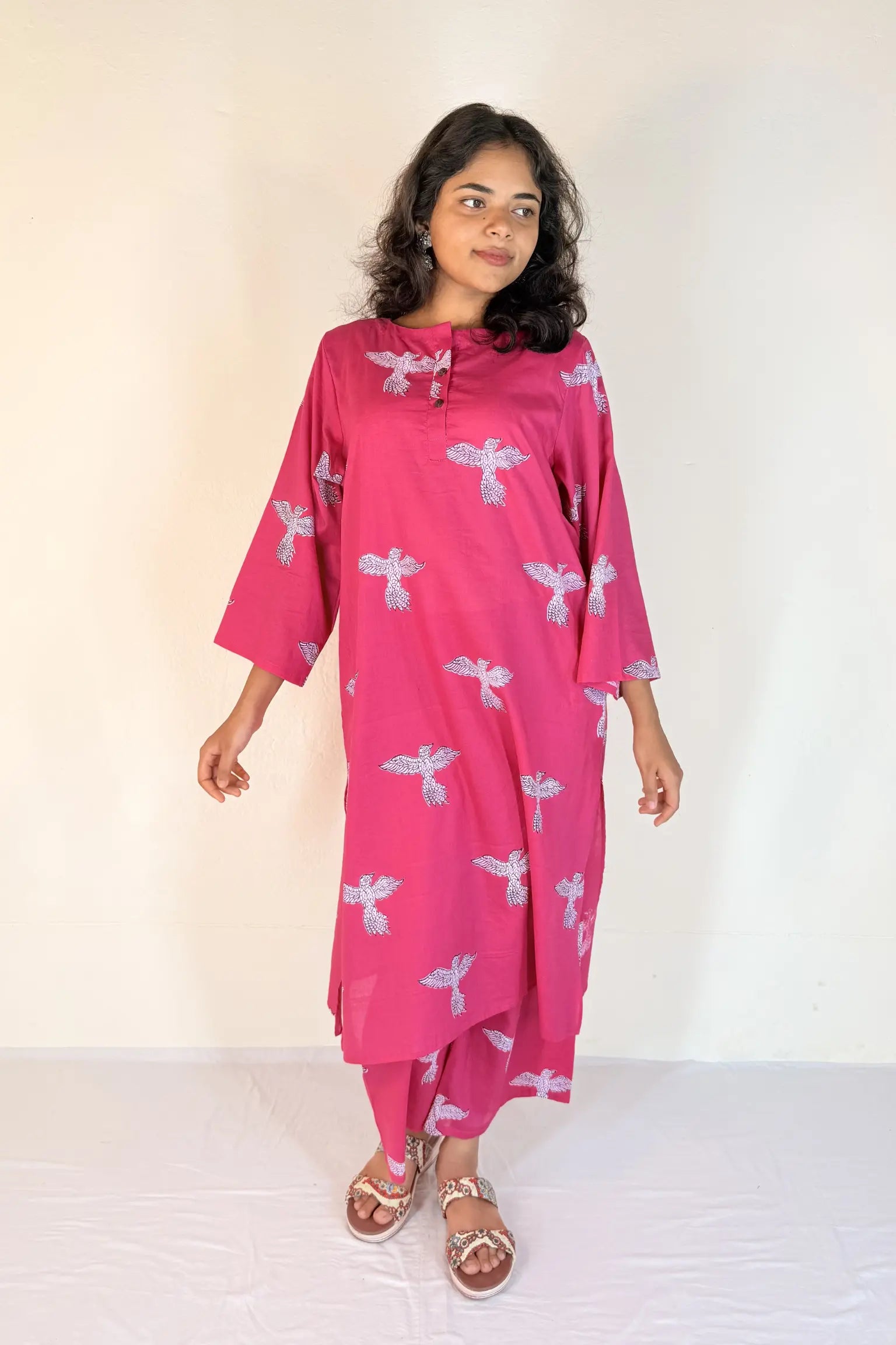 Woman wearing a pink dress with white patterns on a white background