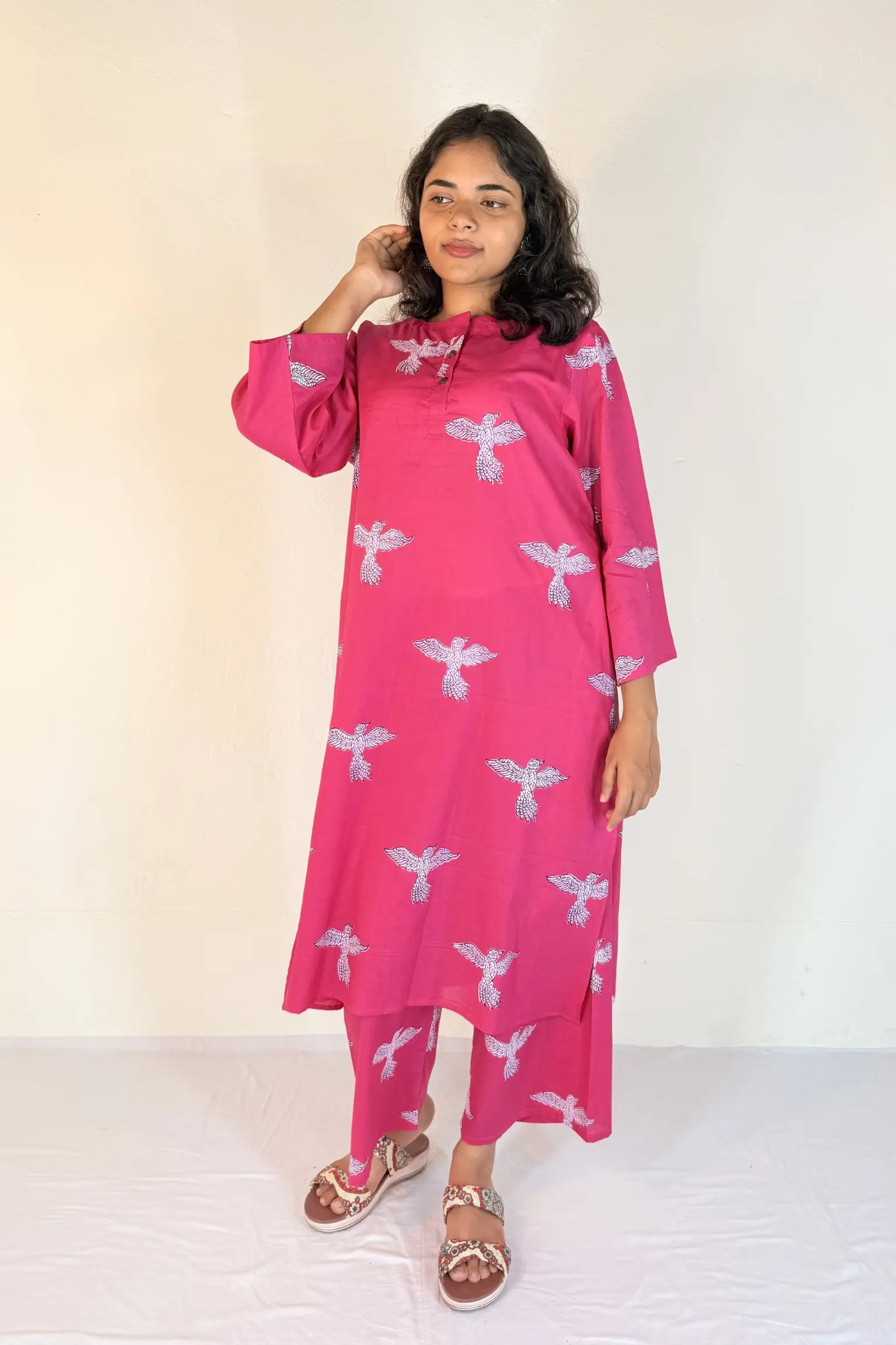 Woman wearing a pink dress with white patterns on a white background