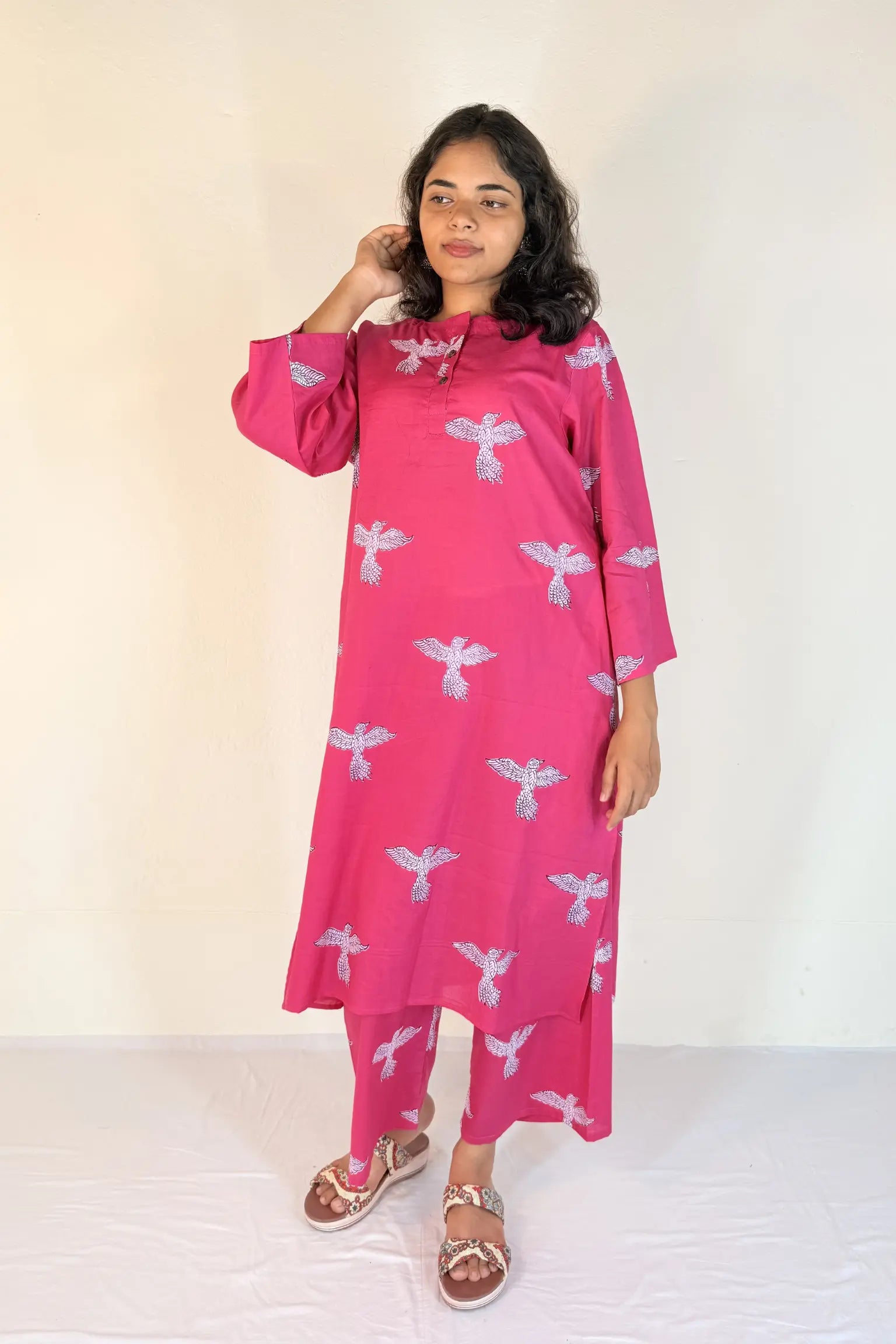 Woman wearing a pink dress with white patterns on a white background