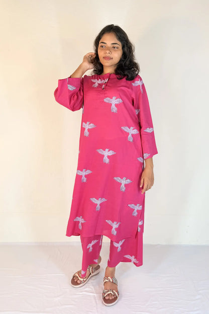 Woman wearing a pink dress with white patterns on a white background