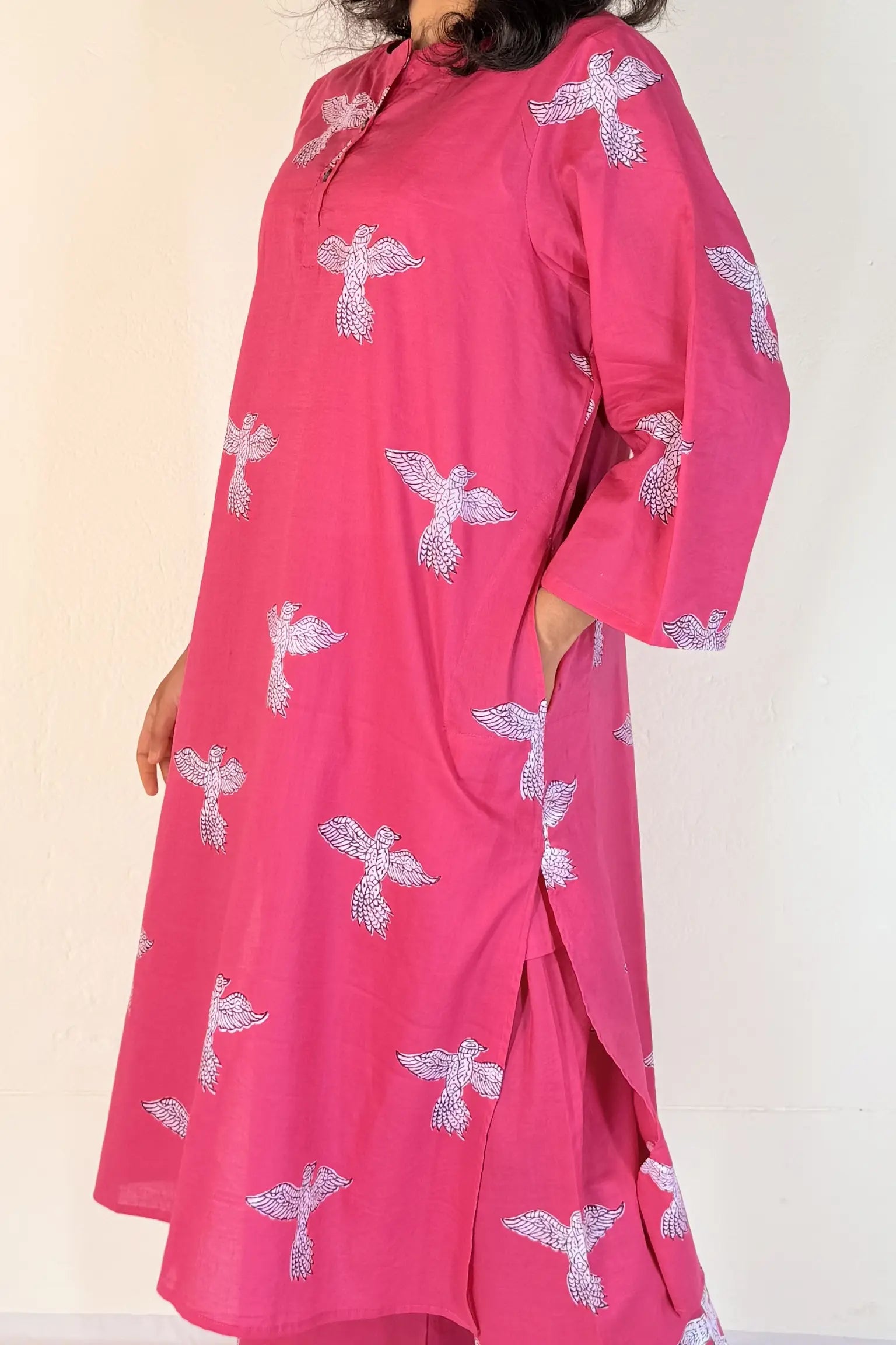 Person wearing a pink outfit with white floral patterns on a plain background