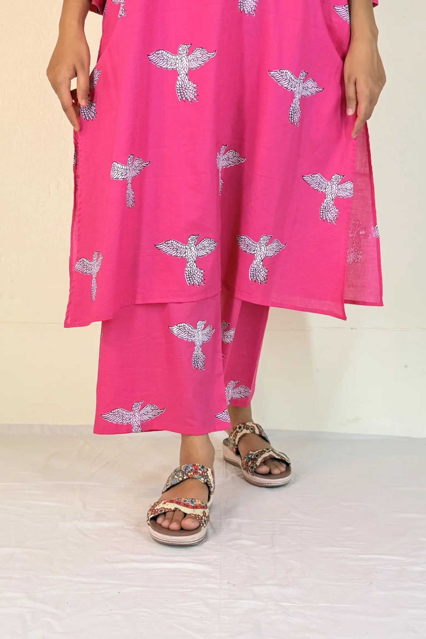 Person wearing a bright pink outfit with silver dragonfly patterns on a beige background