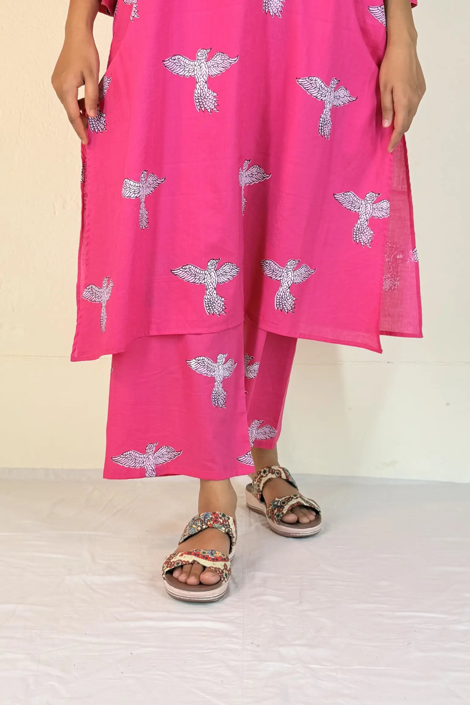 Person wearing a bright pink outfit with silver dragonfly patterns on a beige background