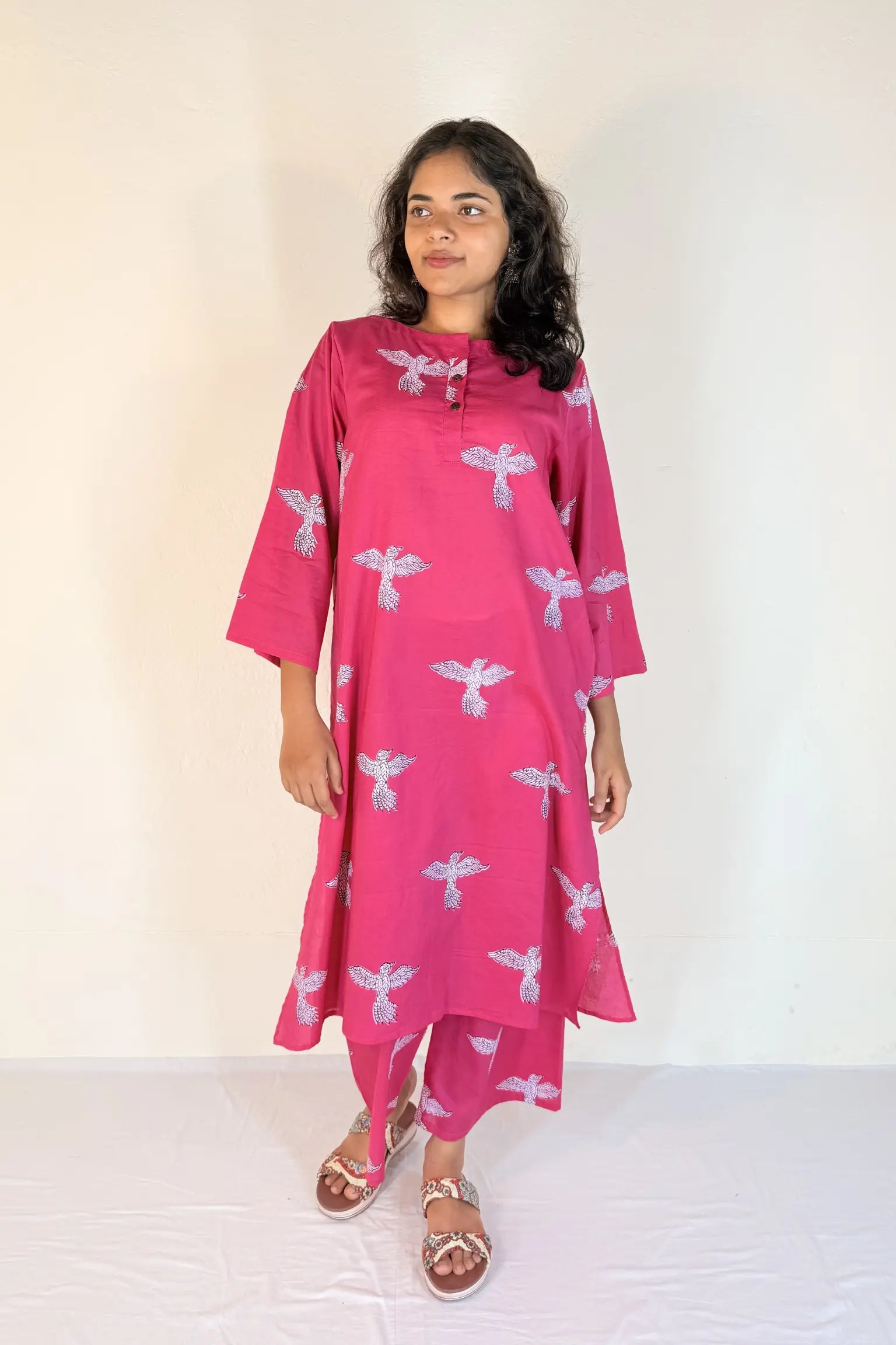 Woman wearing a pink kurta with white patterns on a white background