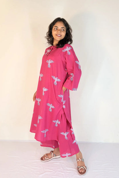 Woman wearing a pink dress with white patterns on a white background
