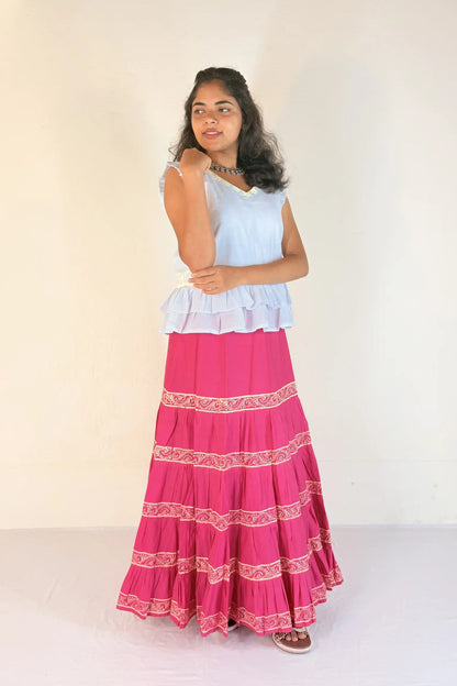 Woman wearing a white top and pink skirt with white patterns on a white background