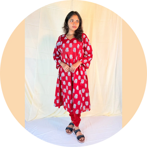 Woman wearing a red floral dress against a white curtain background