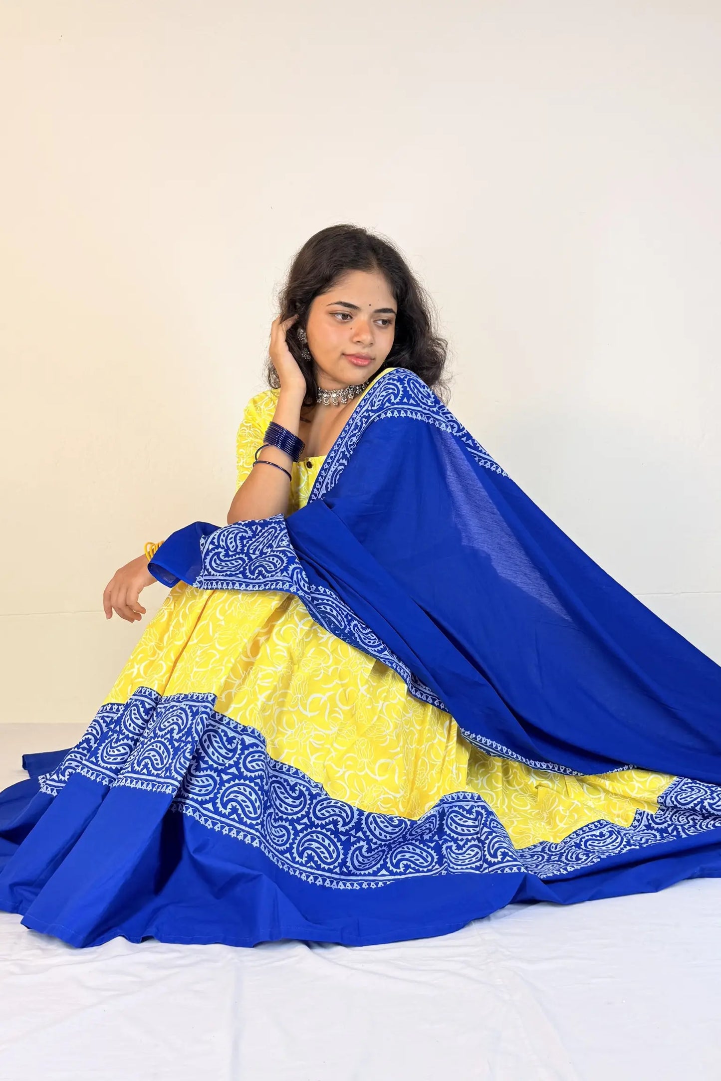 Woman wearing a blue and yellow traditional outfit with a white background