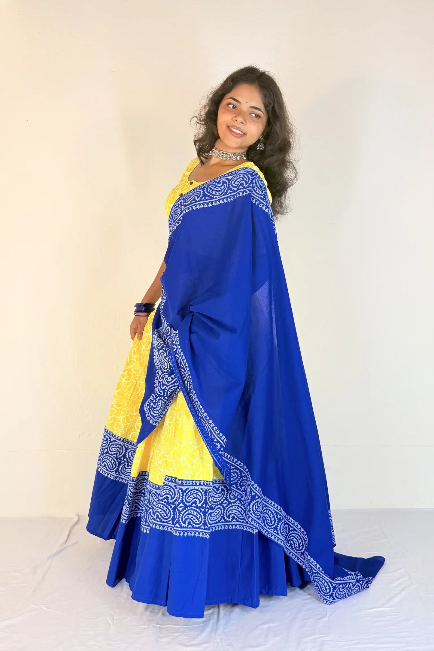 Woman wearing a blue and yellow Gopi Skirt Set with a white background