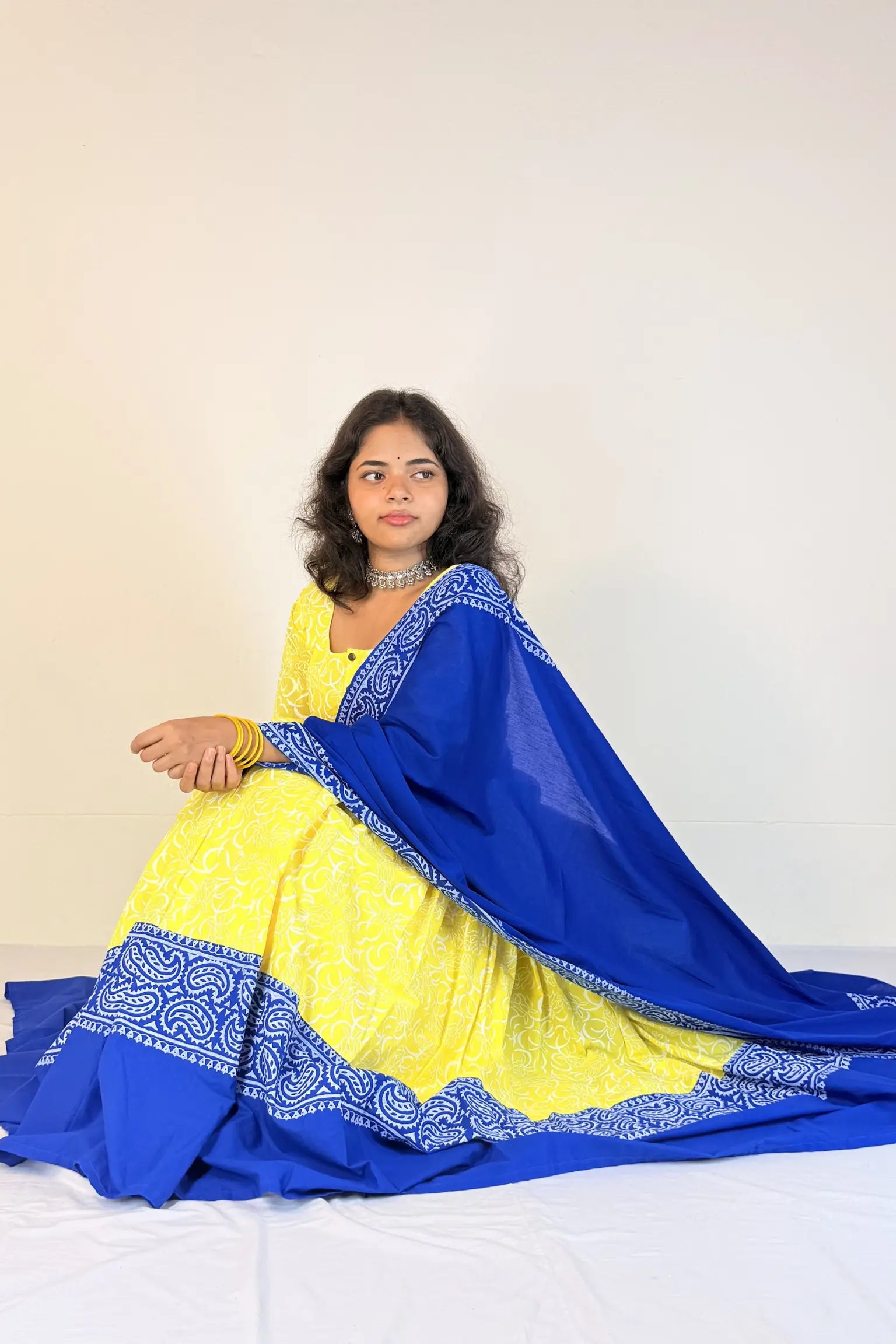 Woman wearing a yellow and blue traditional outfit on a white background