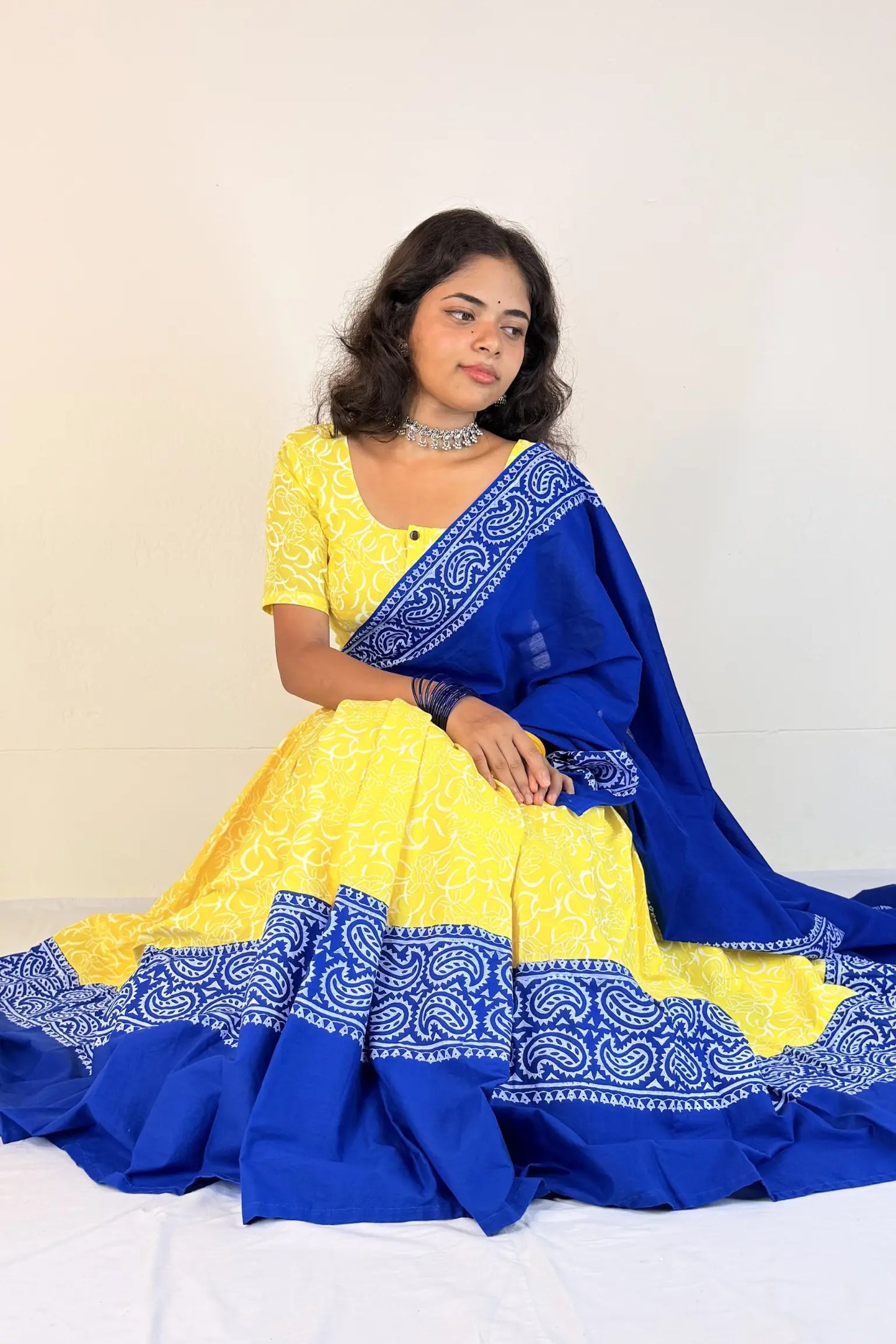 Woman wearing a yellow and blue traditional outfit with a white background
