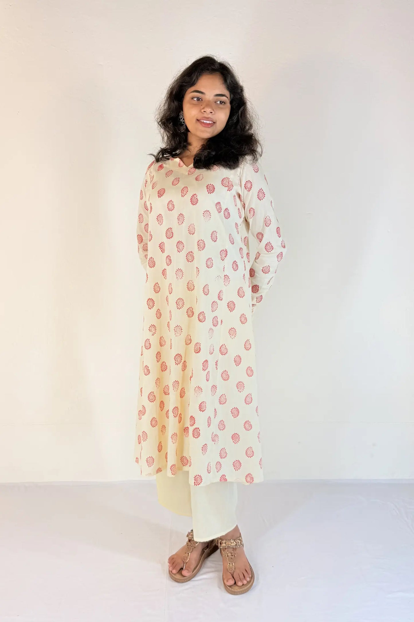 Woman wearing a floral kurta with white pants on a plain background