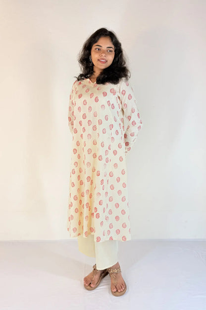 Woman wearing a floral kurta with white pants on a plain background