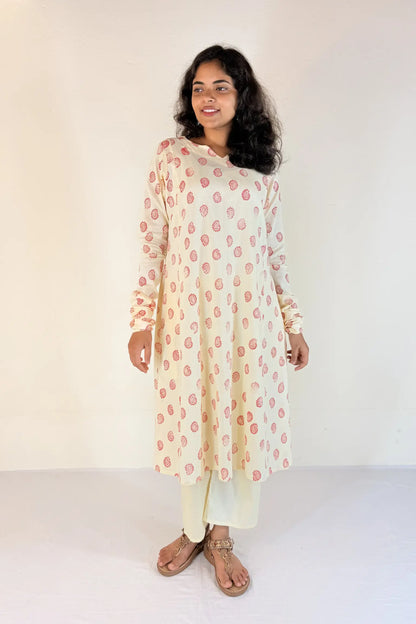 Woman wearing a floral kurta with white pants against a plain background