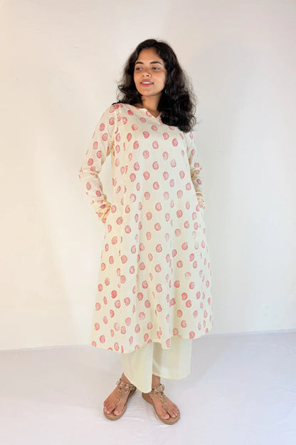 Woman wearing a floral kurta with white pants against a plain background