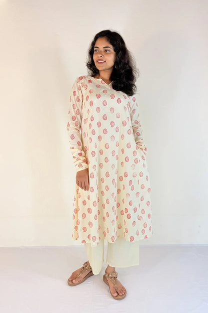 Woman wearing a floral kurta with white pants against a plain background