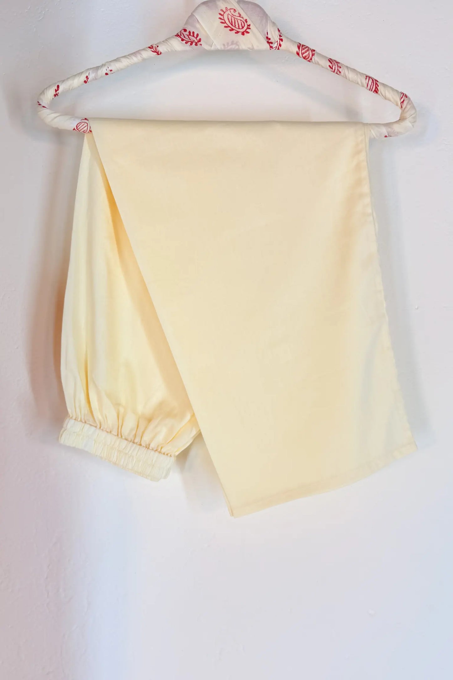 off white pants on a hanger with a beige background