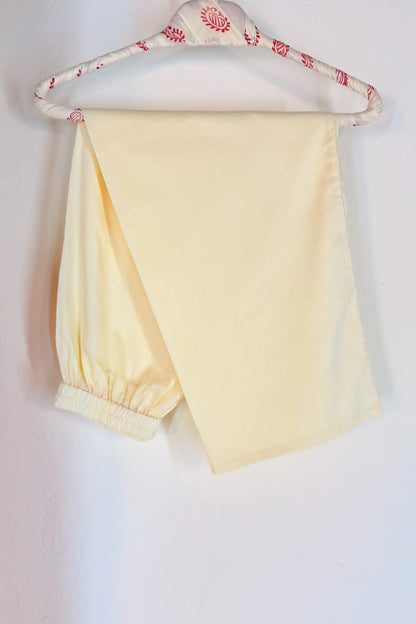 off white pants on a hanger with a beige background