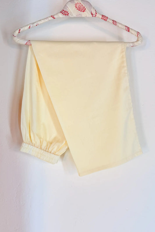 off white pants on a hanger with a beige background