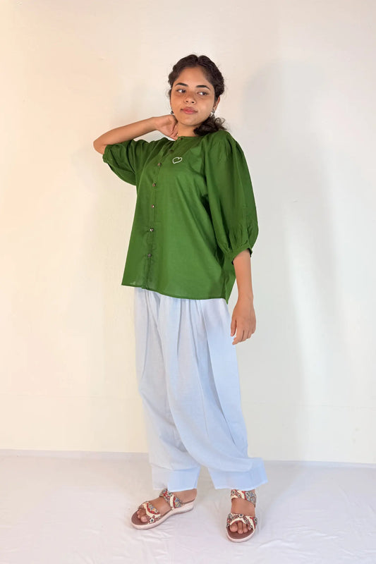 Person wearing a green top and light blue pants against a white background