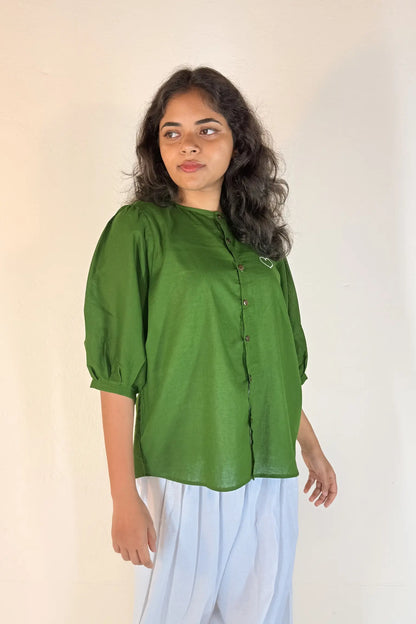 Woman wearing a green blouse with a plain background